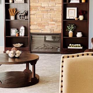 A cozy living room featuring a stylish bookshelf, a warm fireplace, and a modern coffee table.