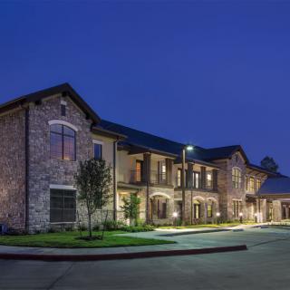 A well-lit building exterior at dusk with a clear sky.