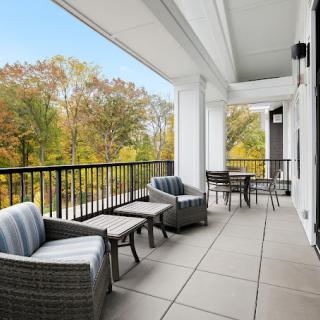A spacious balcony with comfortable outdoor seating and a scenic view of trees.