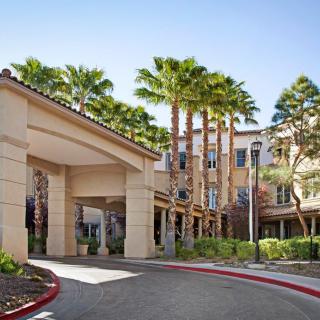 A hotel entrance surrounded by tall palm trees and landscaped gardens.