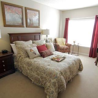 A cozy and well-decorated bedroom with a comfortable bed, artwork on the walls, and natural light coming through the window.