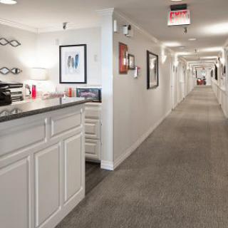 A modern interior hallway with a reception desk and framed art on the walls.