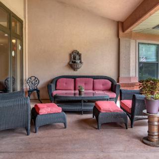 A cozy outdoor patio setup featuring wicker furniture with pink cushions, perfect for relaxation.