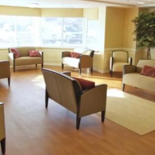 A spacious waiting room with multiple chairs and sofas arranged around a central area.