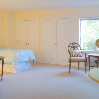 A cozy bedroom with a bed, chairs, and a table near a window.