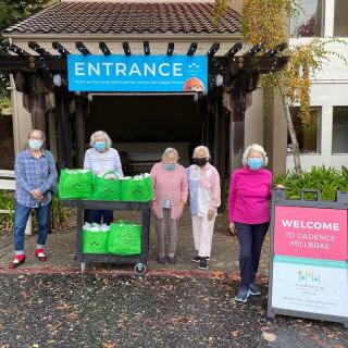 A group of volunteers standing by an entrance with donation bags, all wearing masks.