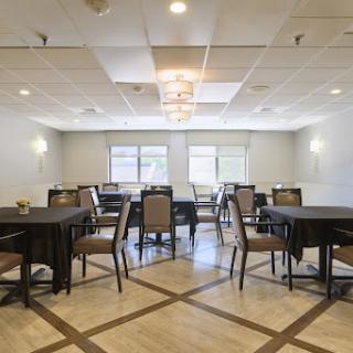 A spacious indoor dining area set up with tables and chairs, illuminated by natural light.