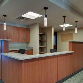 Modern office reception area with wooden desks and pendant lighting.