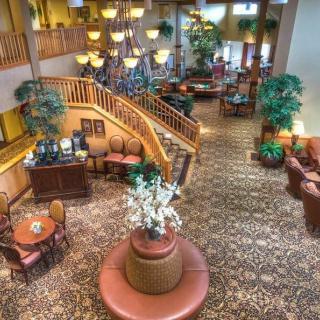 A spacious hotel lobby featuring a grand staircase, cozy seating areas, and elegant lighting.