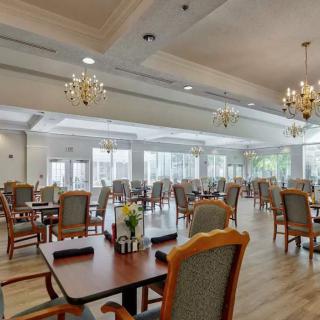A spacious and elegantly decorated dining hall with chandeliers, featuring neatly arranged tables and chairs.