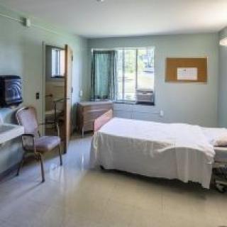 A clean and organized hospital room with a bed, chair, and window.
