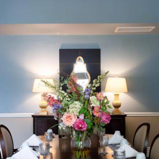 A beautifully arranged dining room featuring a vibrant floral centerpiece and elegant table settings.