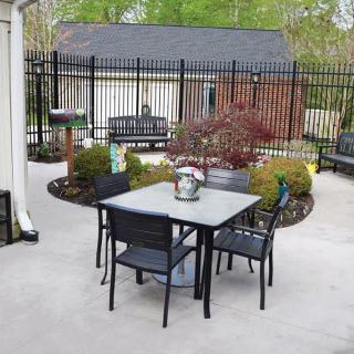 A cozy outdoor patio area with a table and chairs surrounded by greenery.