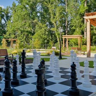 A giant outdoor chess set in a garden setting surrounded by trees.