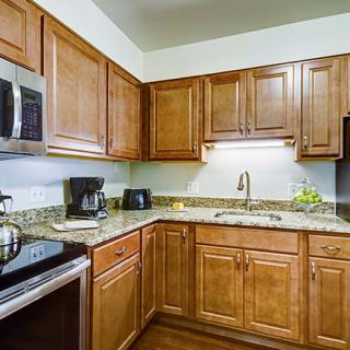 A modern kitchen with wooden cabinets and granite countertops equipped with various appliances.