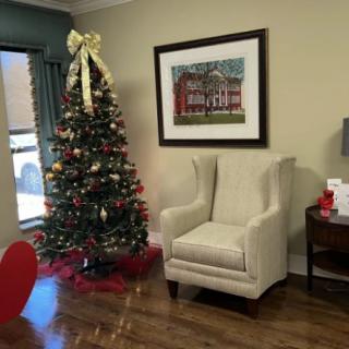 A cozy living room decorated for the holidays with a Christmas tree and an armchair.