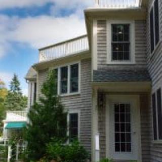 A residential house with a modern exterior featuring large windows and a small balcony.