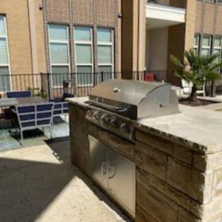 Outdoor patio area with a grill and seating in an apartment complex.