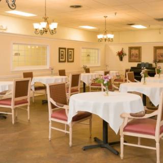 An elegant dining room with neatly arranged tables and chairs, illuminated by warm lighting.