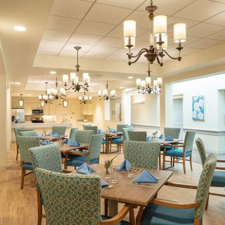 An elegant dining area with chandeliers, neatly arranged tables, and comfortable chairs.