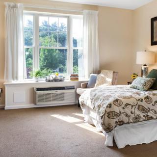 Bright and cozy bedroom with a large window and comfortable furnishings.