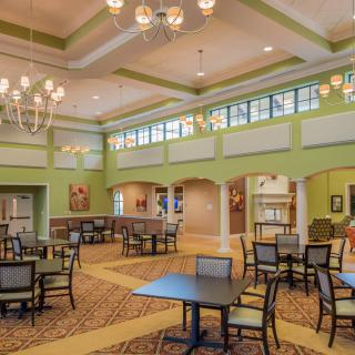 A spacious dining area with elegant chandeliers, green walls, and natural lighting.