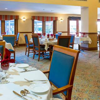 A spacious and elegantly set restaurant dining room with neatly arranged tables and chairs.