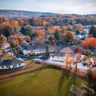 Aerial view of a small town surrounded by vibrant autumn foliage.