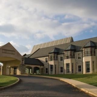 A modern building with a driveway and cloudy sky.
