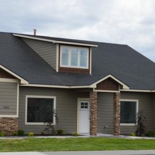 A modern suburban house with a dark roof and stone accents.