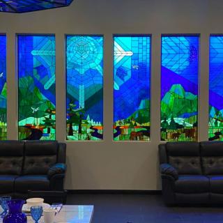A room featuring vibrant stained glass windows with a scenic design, complemented by comfortable sofas.