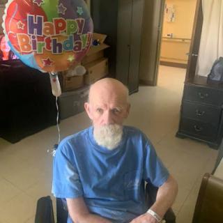 An elderly man celebrating his birthday with a colorful balloon.