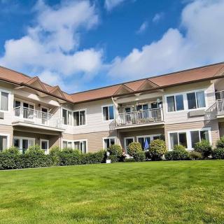 A two-story building with a well-maintained lawn under a partly cloudy sky.