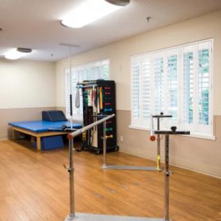A well-equipped physical therapy room with exercise equipment and a padded table.