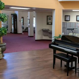 A spacious lobby area with a piano and decorative plants.