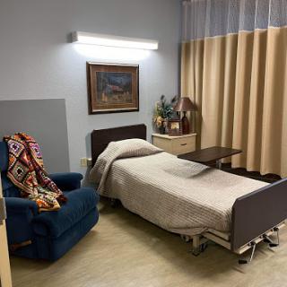 A cozy hospital room featuring a bed, a comfortable chair, and soft lighting.