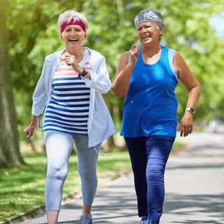 Two senior women walking in a park, enjoying exercise and a healthy lifestyle.