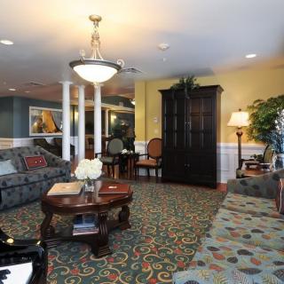 A cozy living room with elegant furniture, featuring a chandelier, sofas, and a coffee table.