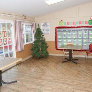 An empty classroom decorated with a Christmas tree and bulletin board.