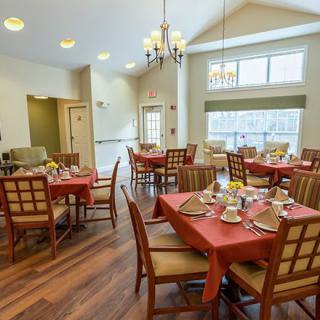 A well-lit dining area with multiple tables and chairs, elegantly set for a meal.