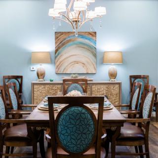A stylish dining room with a large wooden table, upholstered chairs, and elegant lighting.