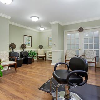 A well-organized hair salon interior featuring styling chairs, dryers, and a waiting area.