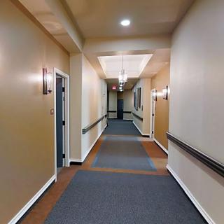 A well-lit hallway with doors and carpeted flooring.