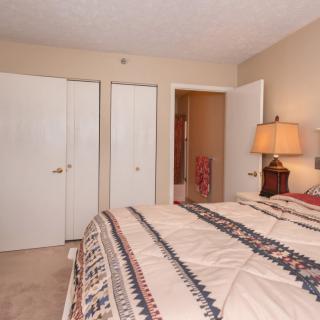 A cozy bedroom with a bed, lamp, and closet doors.