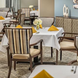A well-arranged dining area with elegantly set tables and chairs, complete with decorative elements.