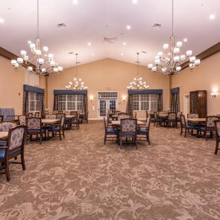 Spacious dining room with elegant chandeliers and neatly arranged tables and chairs.