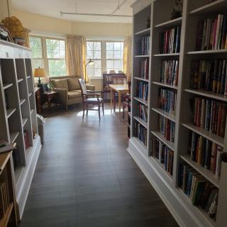 A cozy library space with bookshelves and a reading area by the windows.