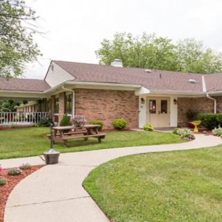 A suburban brick house with a well-maintained lawn and a curved walkway.