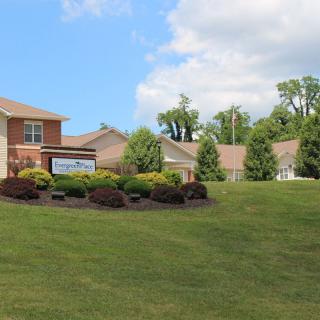 A suburban neighborhood with well-maintained lawns and neatly arranged houses under a partially cloudy sky.