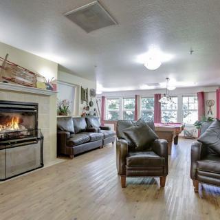 A cozy living room with a fireplace, leather chairs, and a pool table.